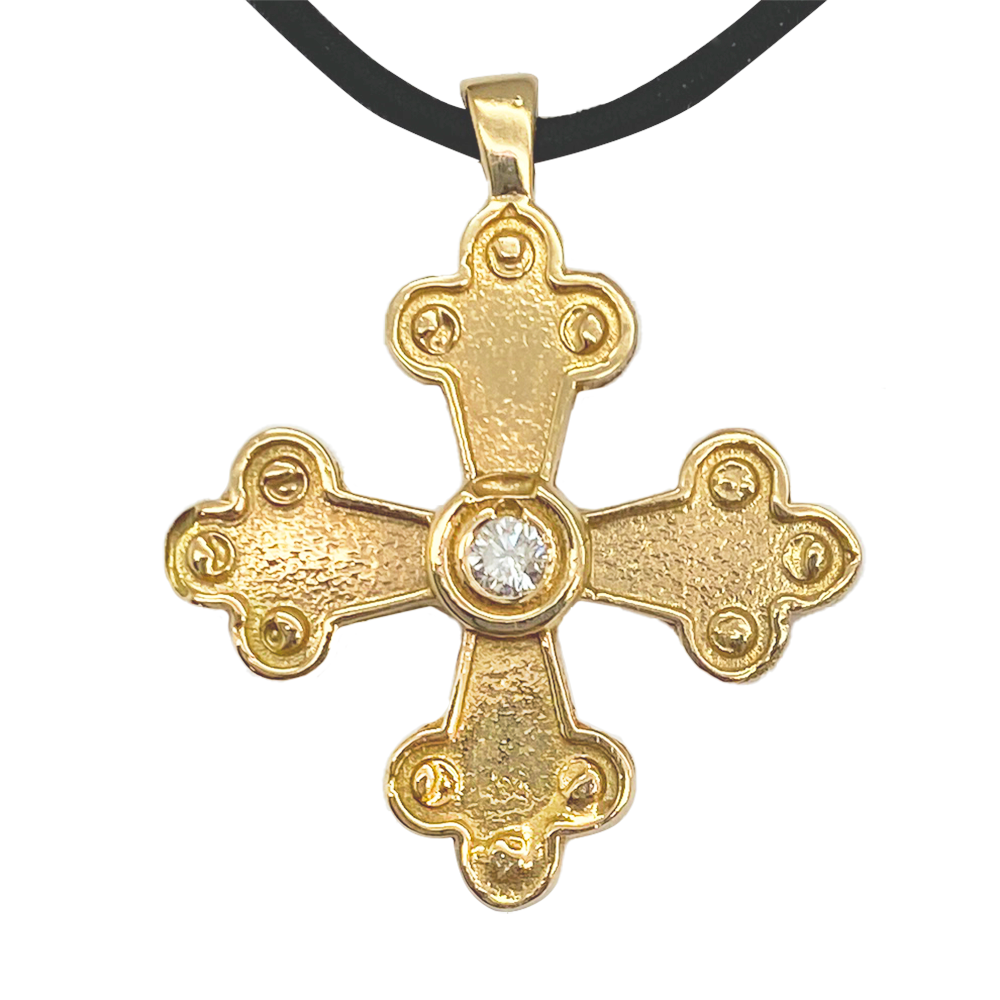 Gold cross pendant with a center gemstone on a white background