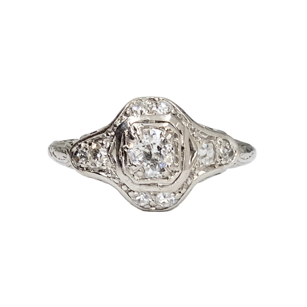 Silver diamond ring featuring a rectangular center stone surrounded by smaller diamonds in a geometric setting.