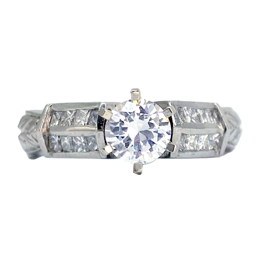 Silver diamond engagement ring with a round-cut center stone and trapezoid-shaped side stones, on a white background