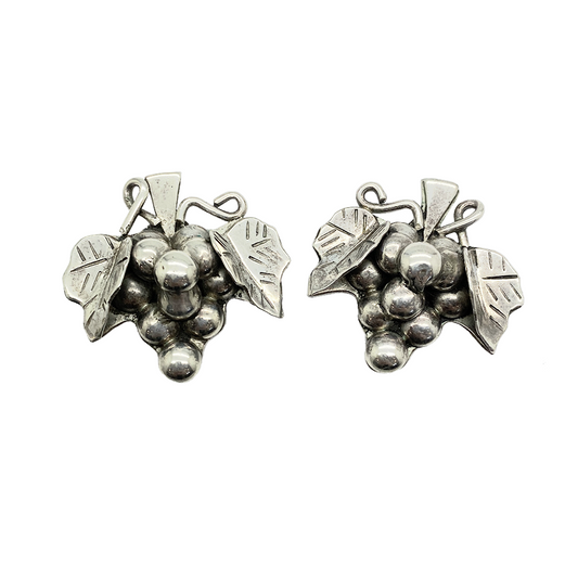 Silver earrings in the form of a grapevine with leaves and clusters of grapes.