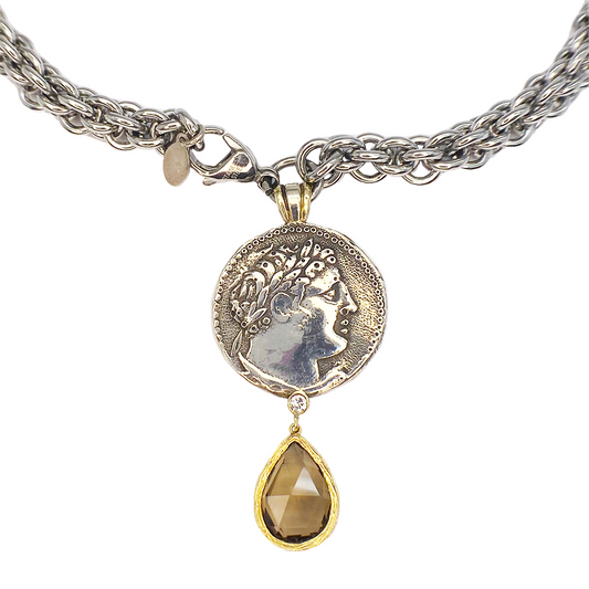 Silver chain necklace with a large circular coin pendant featuring a woman's profile in profile.