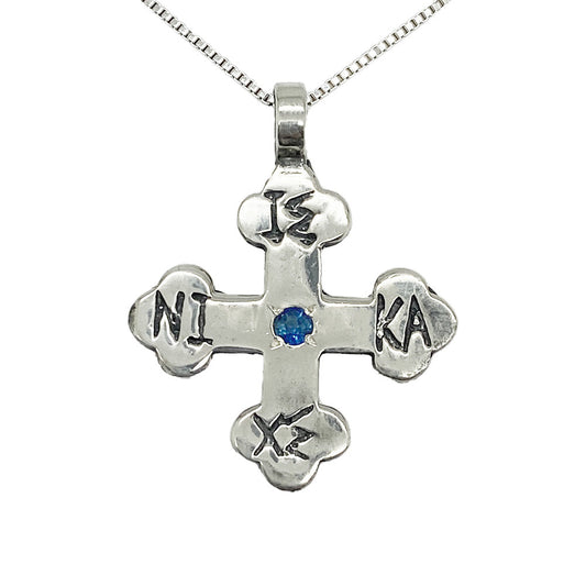 Silver cross pendant with gemstone on a white background