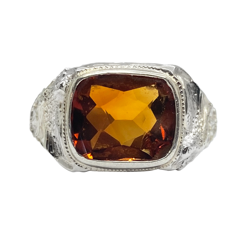 Silver ring with a large, cushion-cut, synthetic orange sapphire set in a platinum bezel.