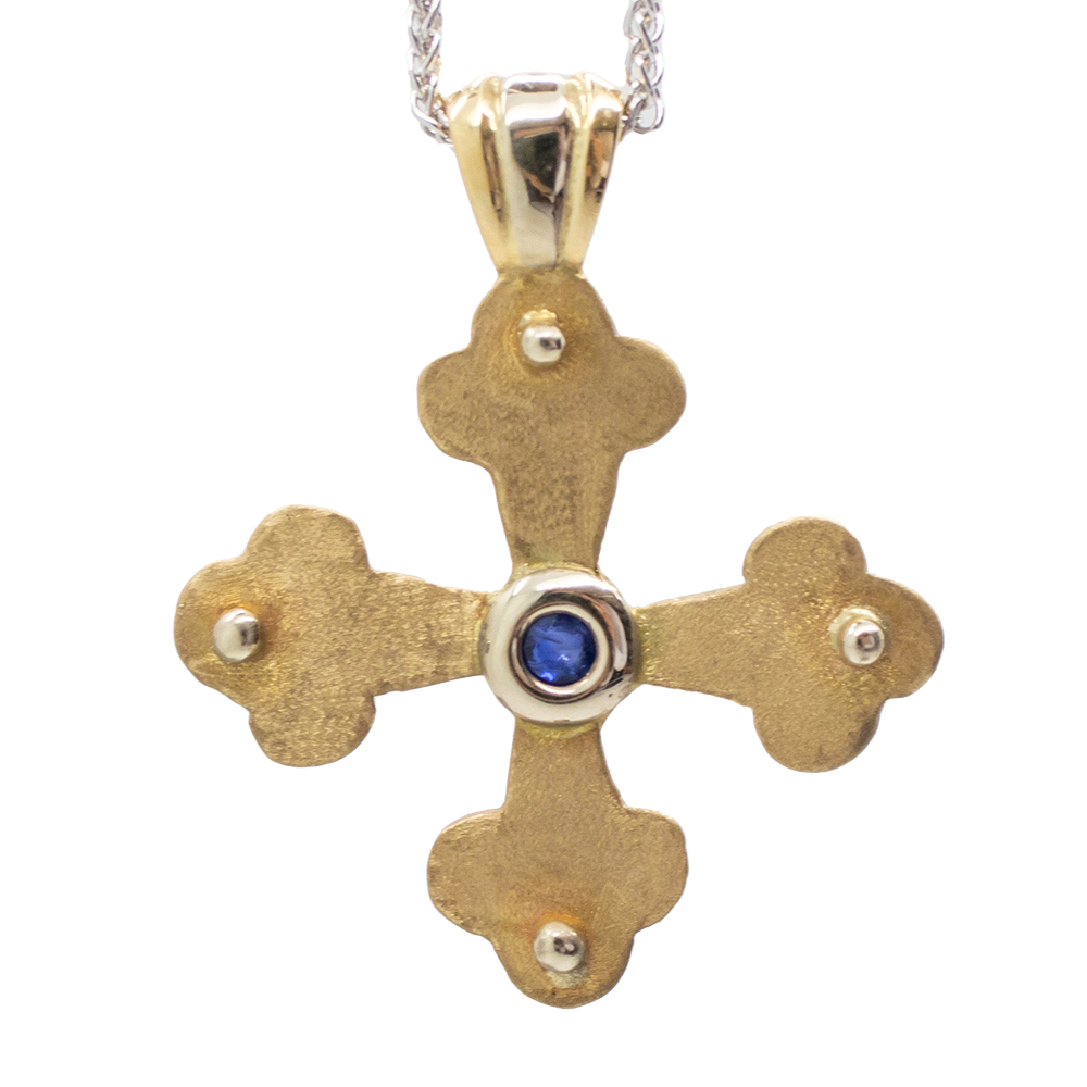 Gold Byzantine Orthodox cross pendant with a gold-toned metal body and a small blue gemstone at the center.