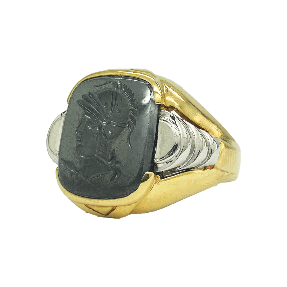  Vintage gold men's ring with a rectangular hematite intaglio featuring a detailed profile of a helmeted warrior. The ring has a textured gold band with a contrasting white metal inlay.