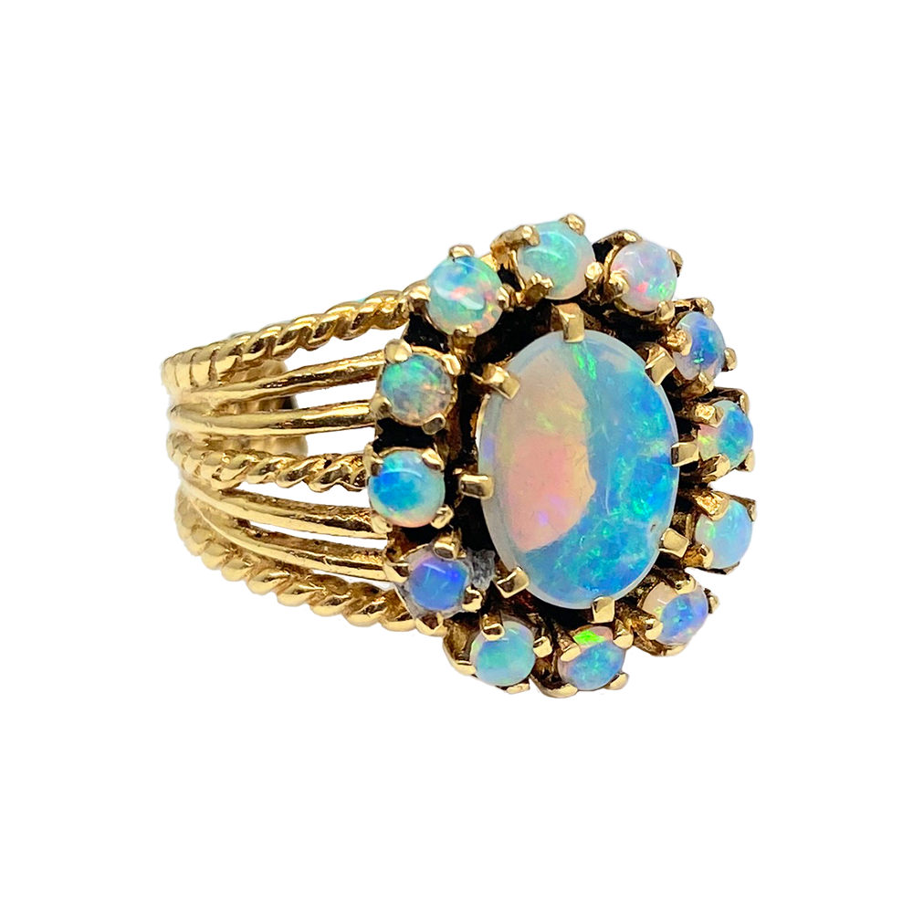 Vintage opal ring with a large oval opal center stone surrounded by smaller opals in a floral arrangement. 