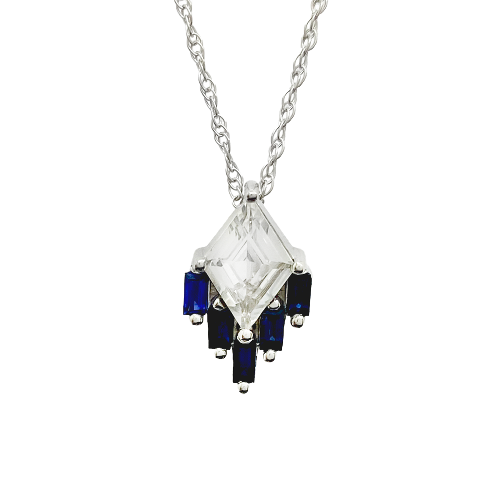 Silver necklace with a large kite-shaped white sapphire in the center, surrounded by four blue sapphire baguettes.