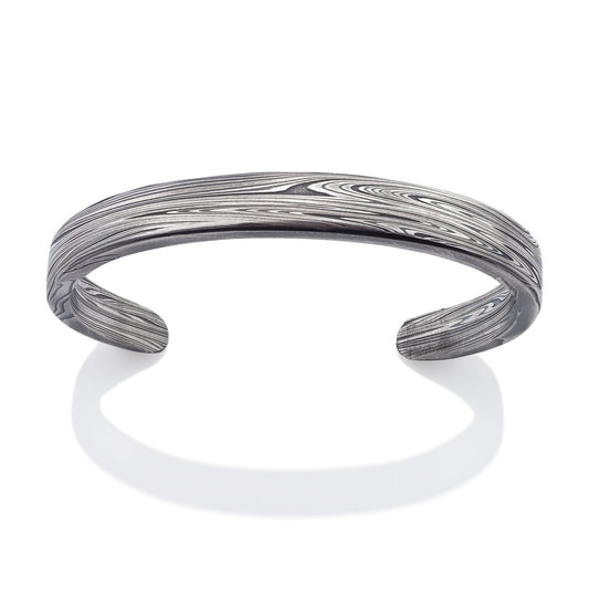 Silver cuff bracelet with Damascus steel pattern on a white background.