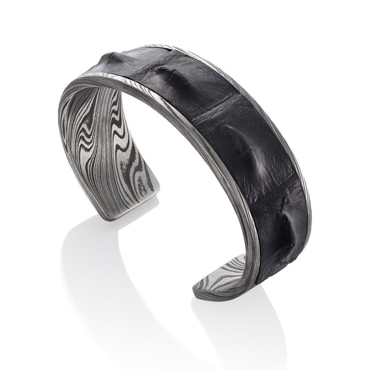 Titanium cuff bracelet with Damascus steel pattern on a white background.