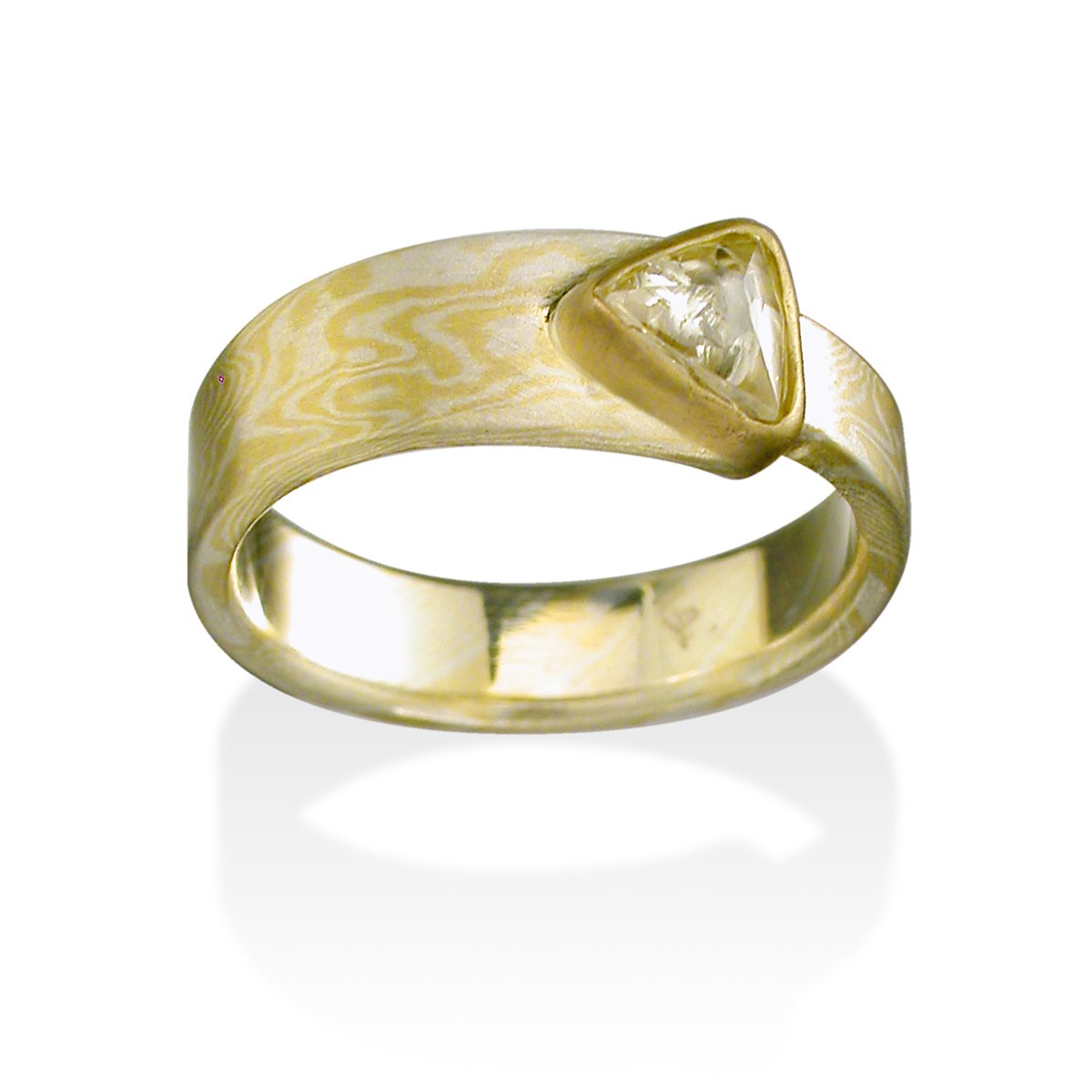 Yellow gold ring with a triangular diamond and a Damascus steel band on a white background