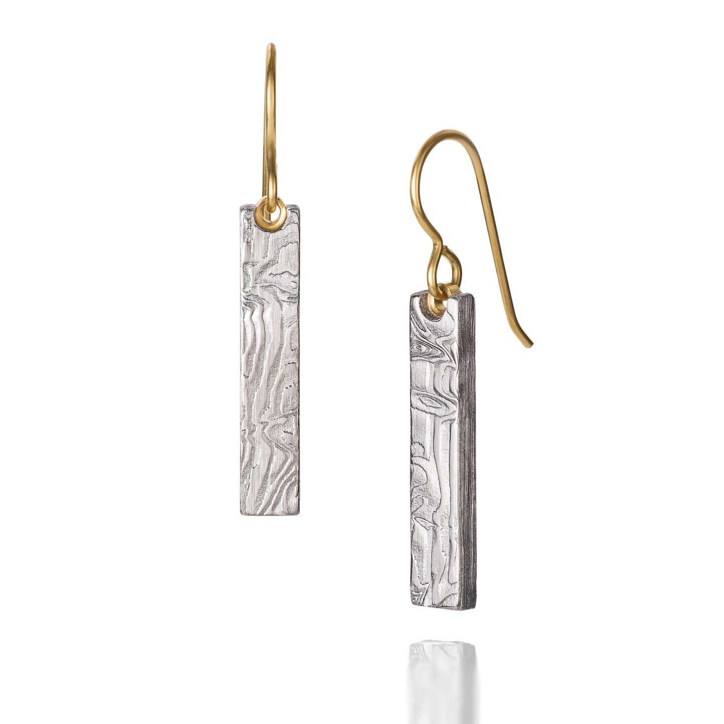 Pair of gold earrings with a damascus steel pattern, on a white background.