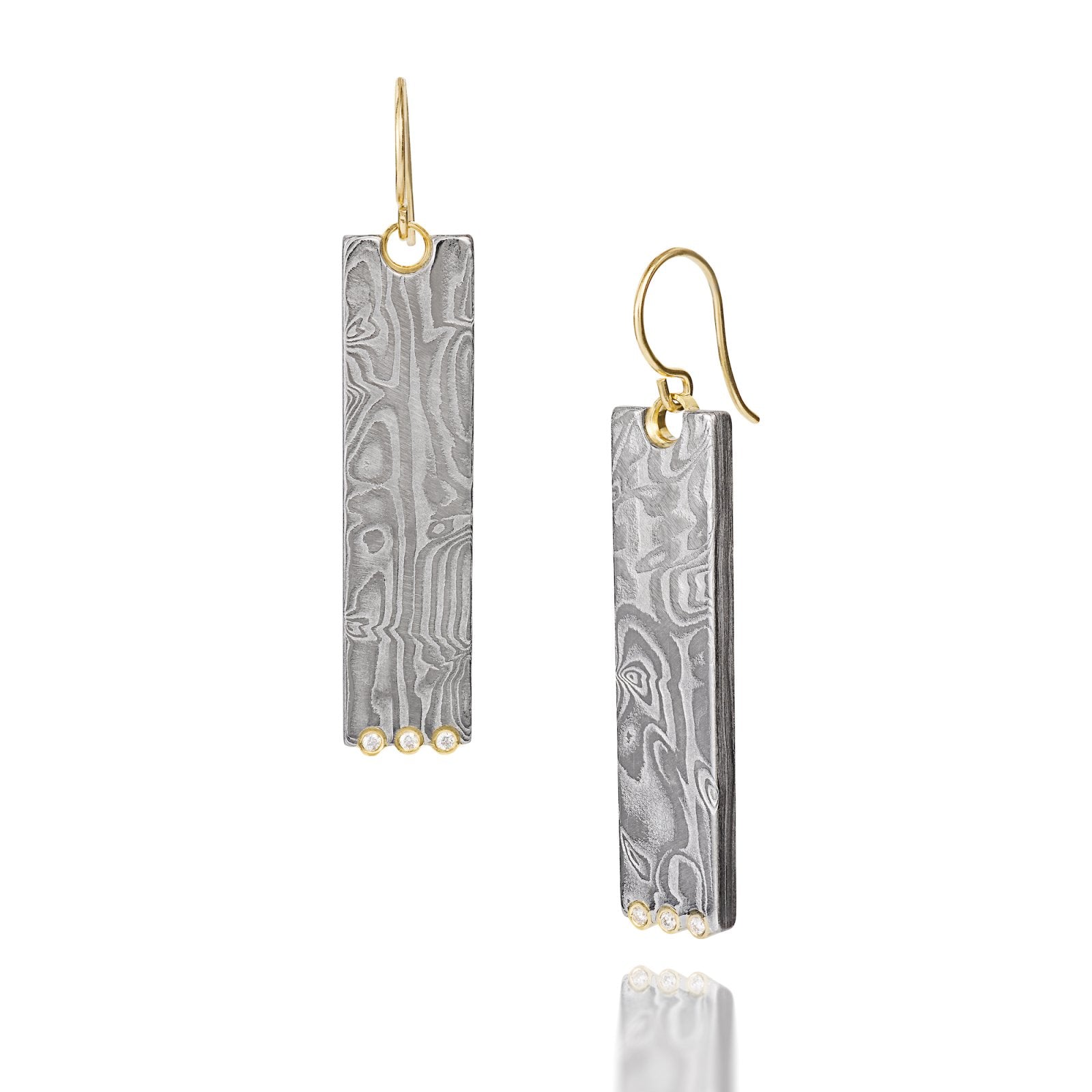 Pair of gold earrings with a damascus steel pattern, on a white background.