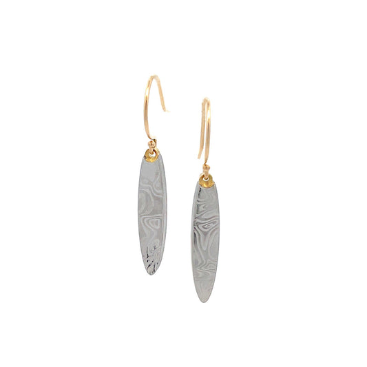 Pair of gold oval shaped earrings with a damascus steel pattern, on a white background.