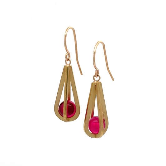 Pair of gold teardrop-shaped earrings with red gemstones inside, on a white background.