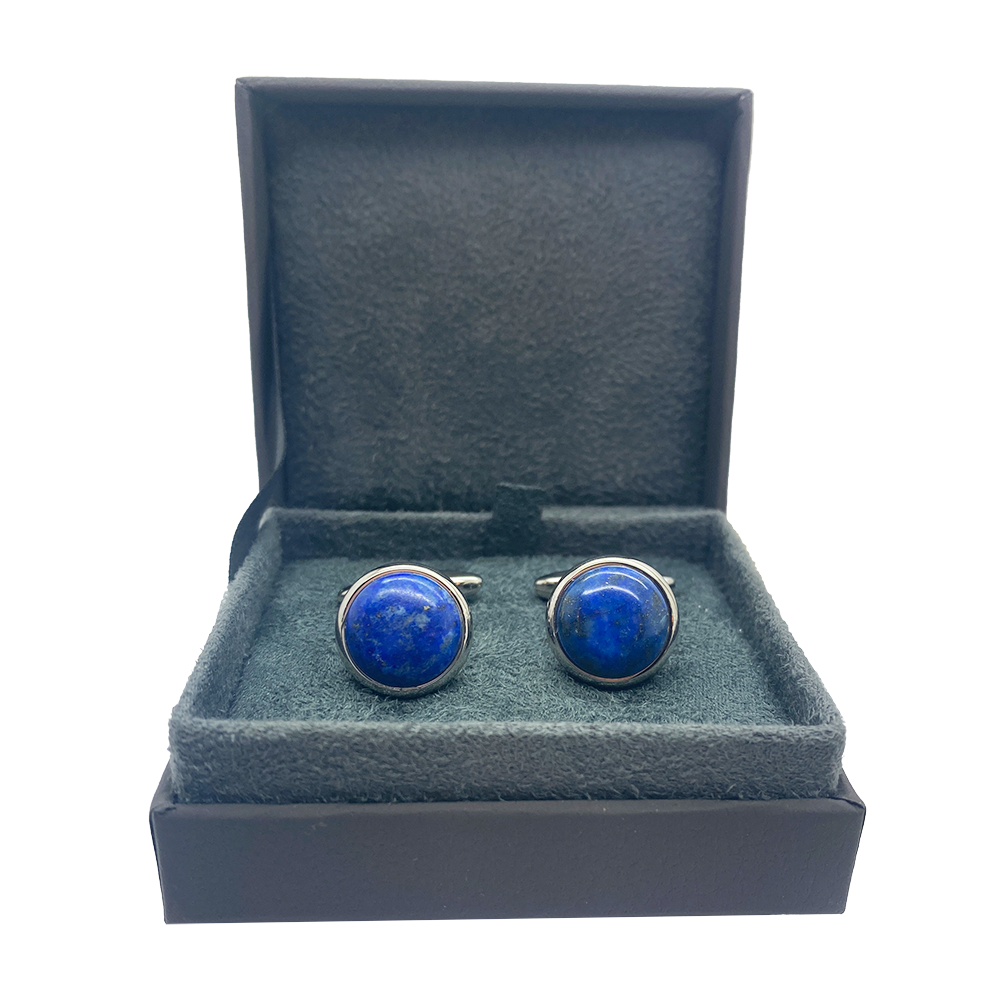 Pair of silver cufflinks with round, blue lapis lazuli stones set in a bezel setting on a jewelry box