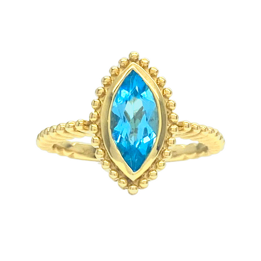 Gold ring with a marquise-cut blue topaz center stone.