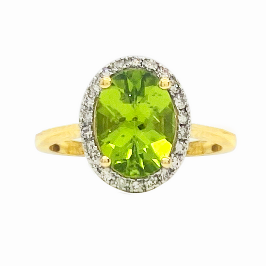 Gold ring with an oval peridot in the center surrounded by diamonds