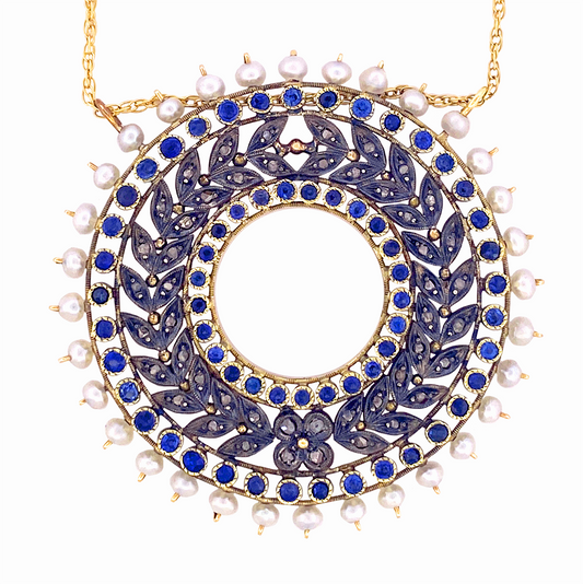 Circular gold pendant adorned with alternating sapphires and diamonds, surrounded by a border of pearls.