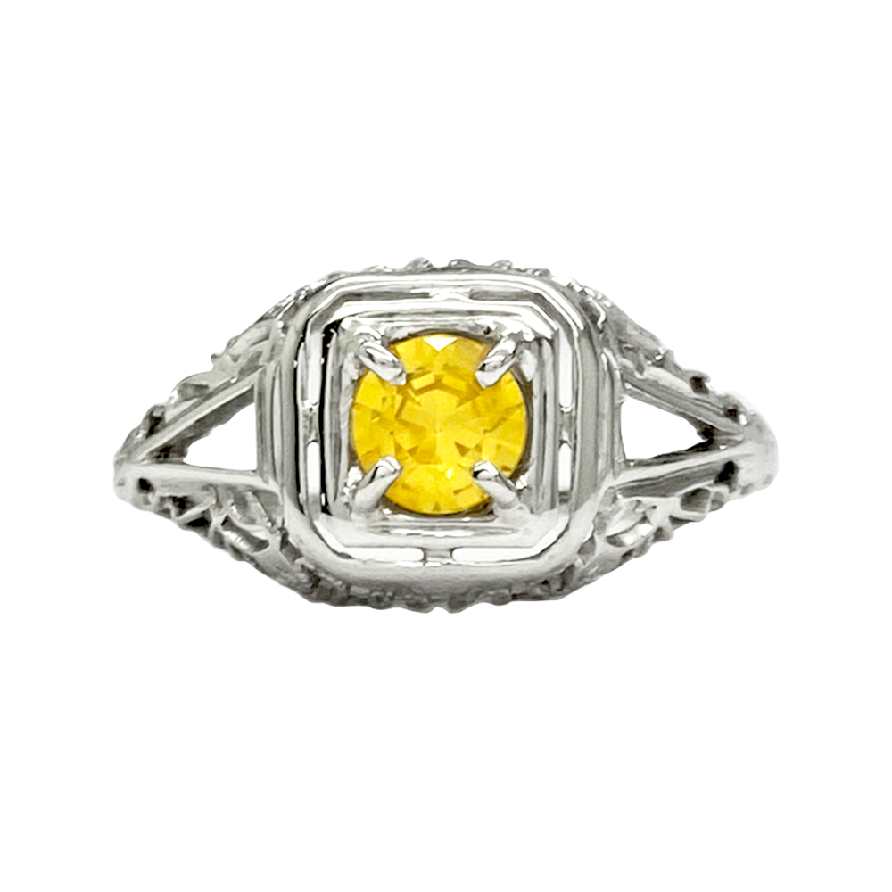 Silver ring with a round yellow sapphire set in a filigree design.