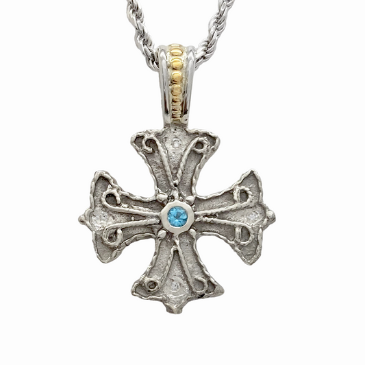 Silver byzantine cross pendant with a blue stone in the center.