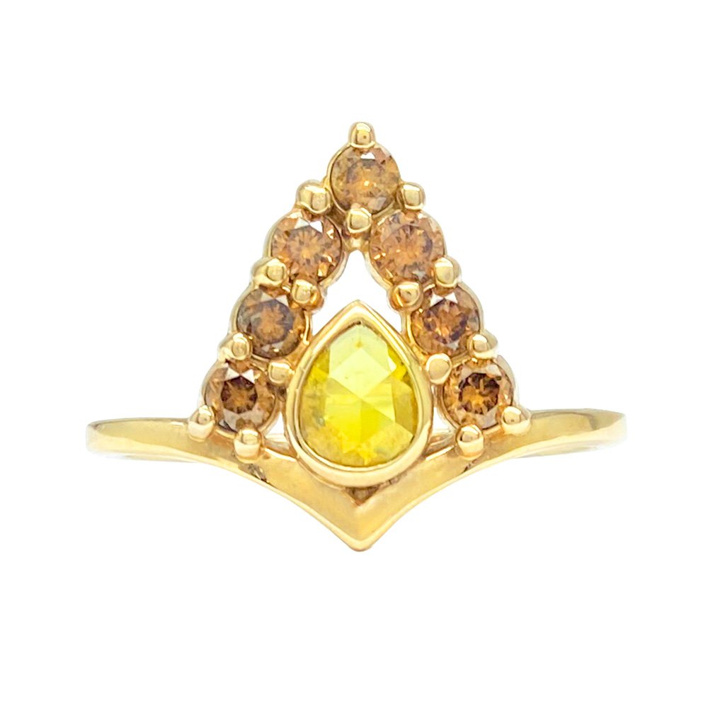 Gold ring with a pear-shaped yellow gemstone in the center. The gemstone is surrounded by smaller, round brown stones in a triangular formation.