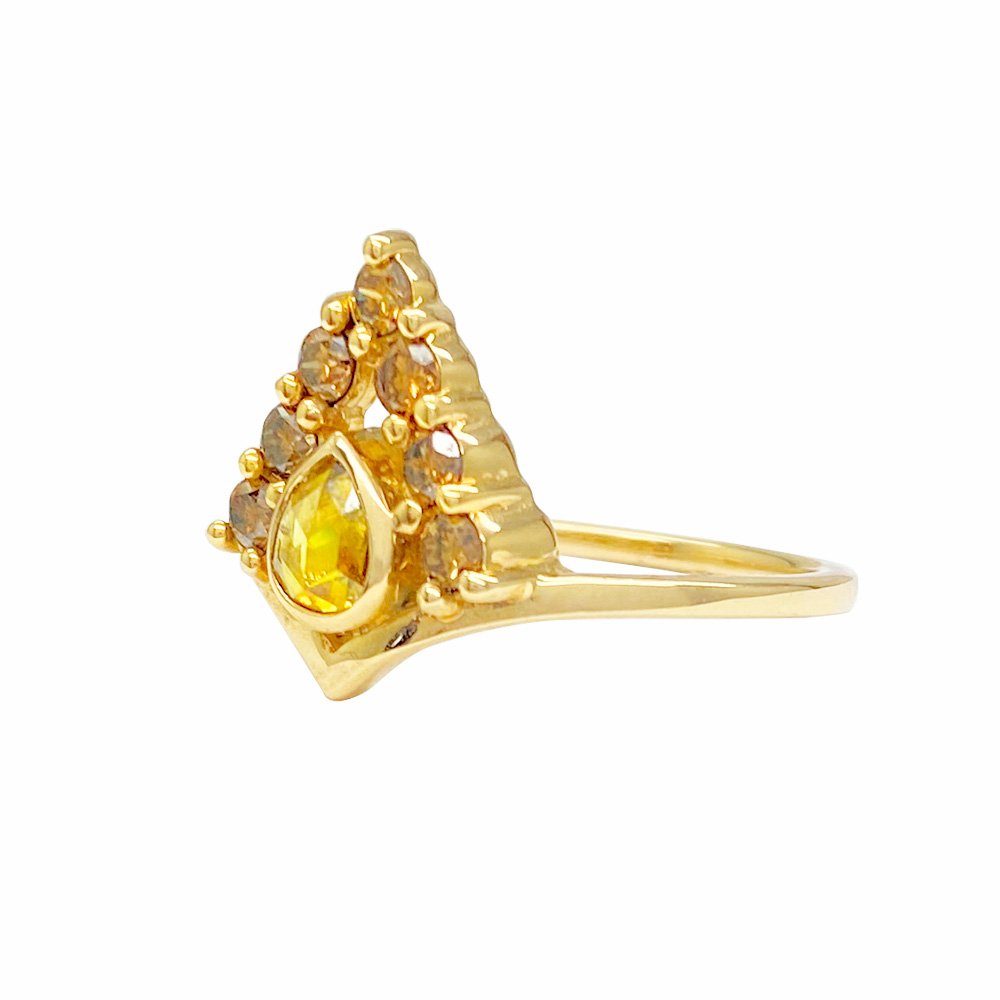 Gold ring with a pear-shaped yellow gemstone in the center. The gemstone is surrounded by smaller, round brown stones in a triangular formation.