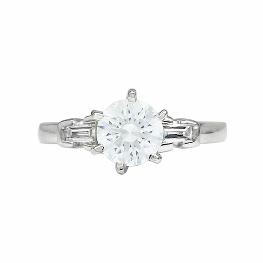 Silver engagement ring with a single, round center diamond and two baguette-cut diamonds on each side.