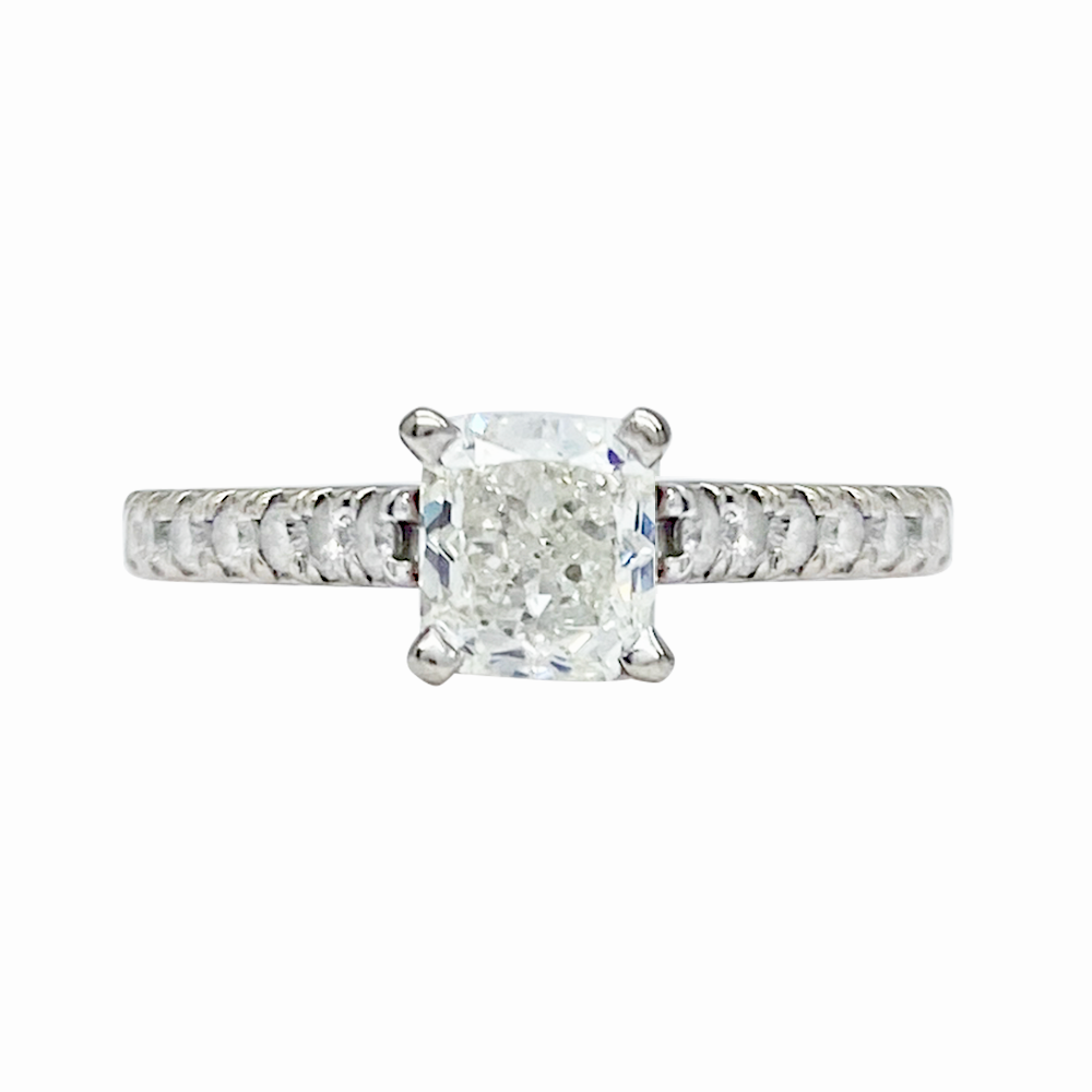 Silver diamond engagement ring with a princess-cut center stone and smaller round diamonds on the band and shank.