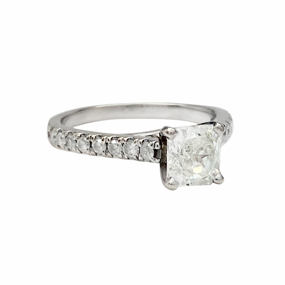 Silver diamond engagement ring with a princess-cut center stone and smaller round diamonds on the band and shank.