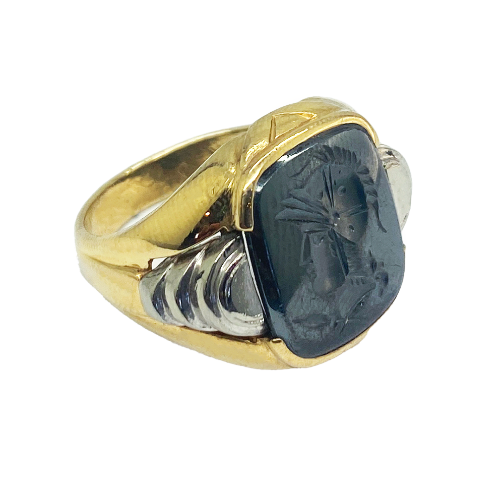  Vintage gold men's ring with a rectangular hematite intaglio featuring a detailed profile of a helmeted warrior. The ring has a textured gold band with a contrasting white metal inlay.