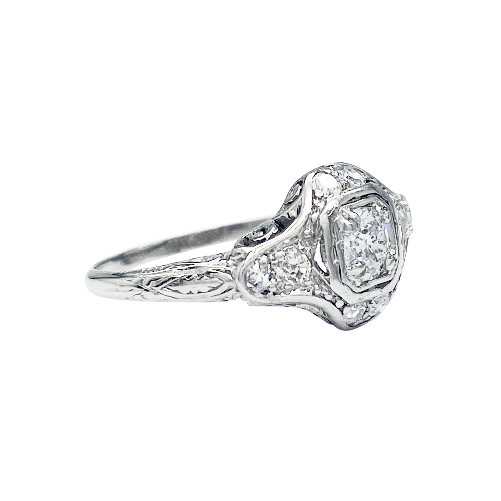 Silver diamond ring featuring a rectangular center stone surrounded by smaller diamonds in a geometric setting.