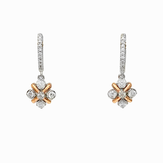 Diamond hoop earrings with a dangling diamond cluster in a rose gold and white gold setting on a white background