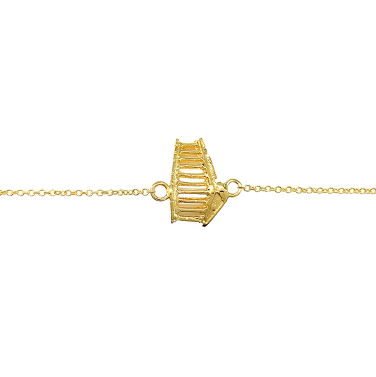 Gold bracelet featuring a unique, architectural design, on a white background 