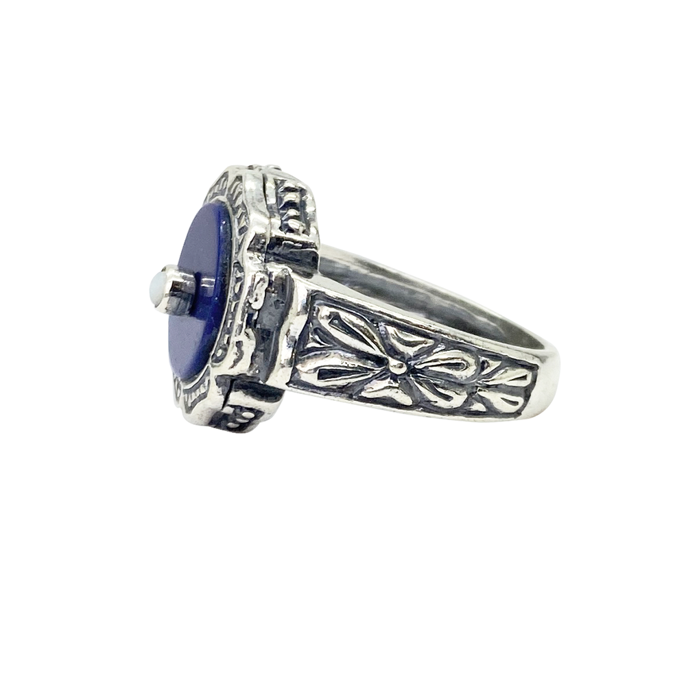 Silver ring with a blue lapis lazuli center stone and intricate filigree detailing, on a white background