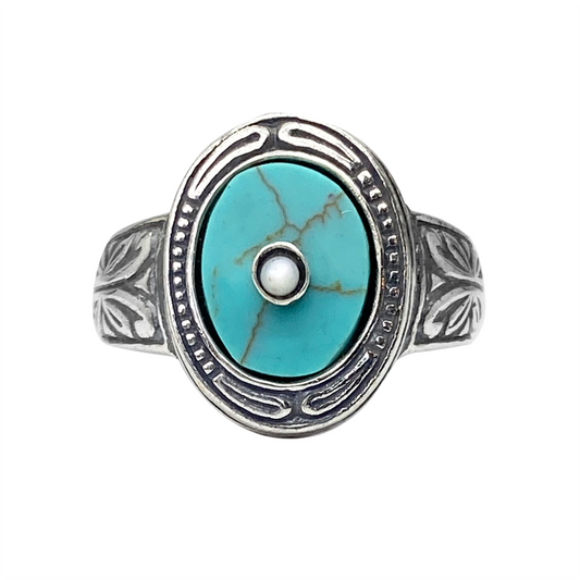 Silver ring with a turquoise center stone and intricate filigree detailing, on a white background