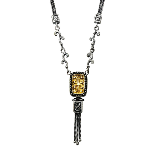 Silver necklace with a gold-plated floral pendant and a silver chain with a tassel, on a white background.