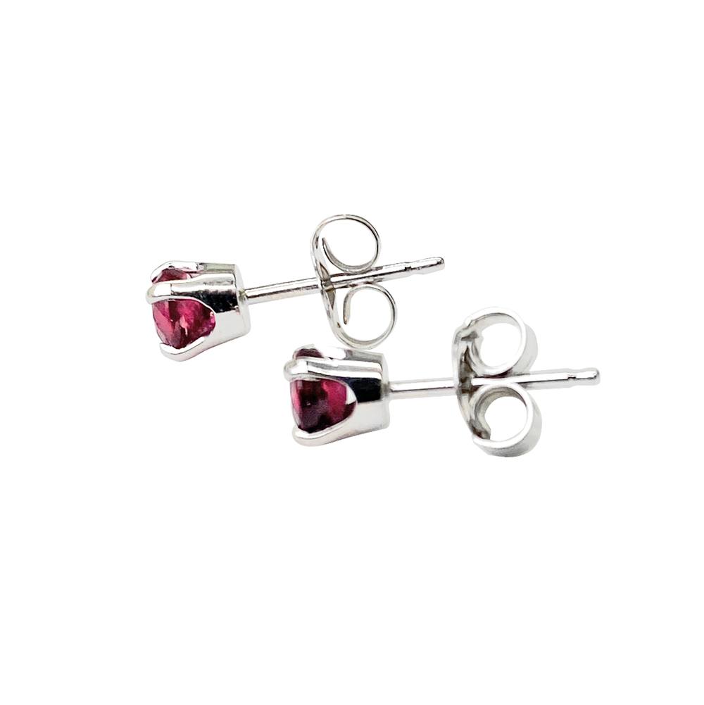 Side view of pair of silver stud earrings with round ruby gemstones on a white background