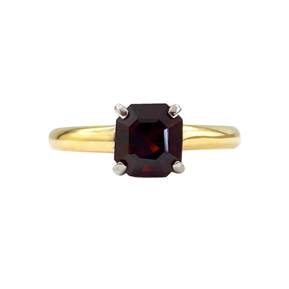 Yellow gold ring with an asscher-cut garnet center stone on a white background.