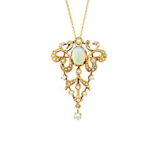 Close-up of a gold necklace with a pendant featuring an opal, pearls, and intricate filigree work, on a white background.