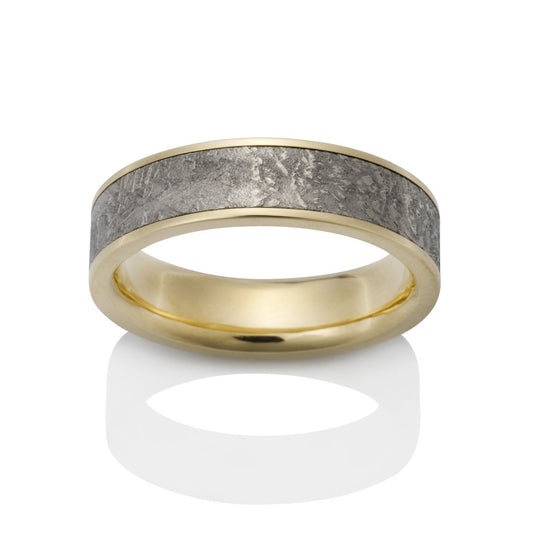 Gold ring with a meteorite inlay on a white background.