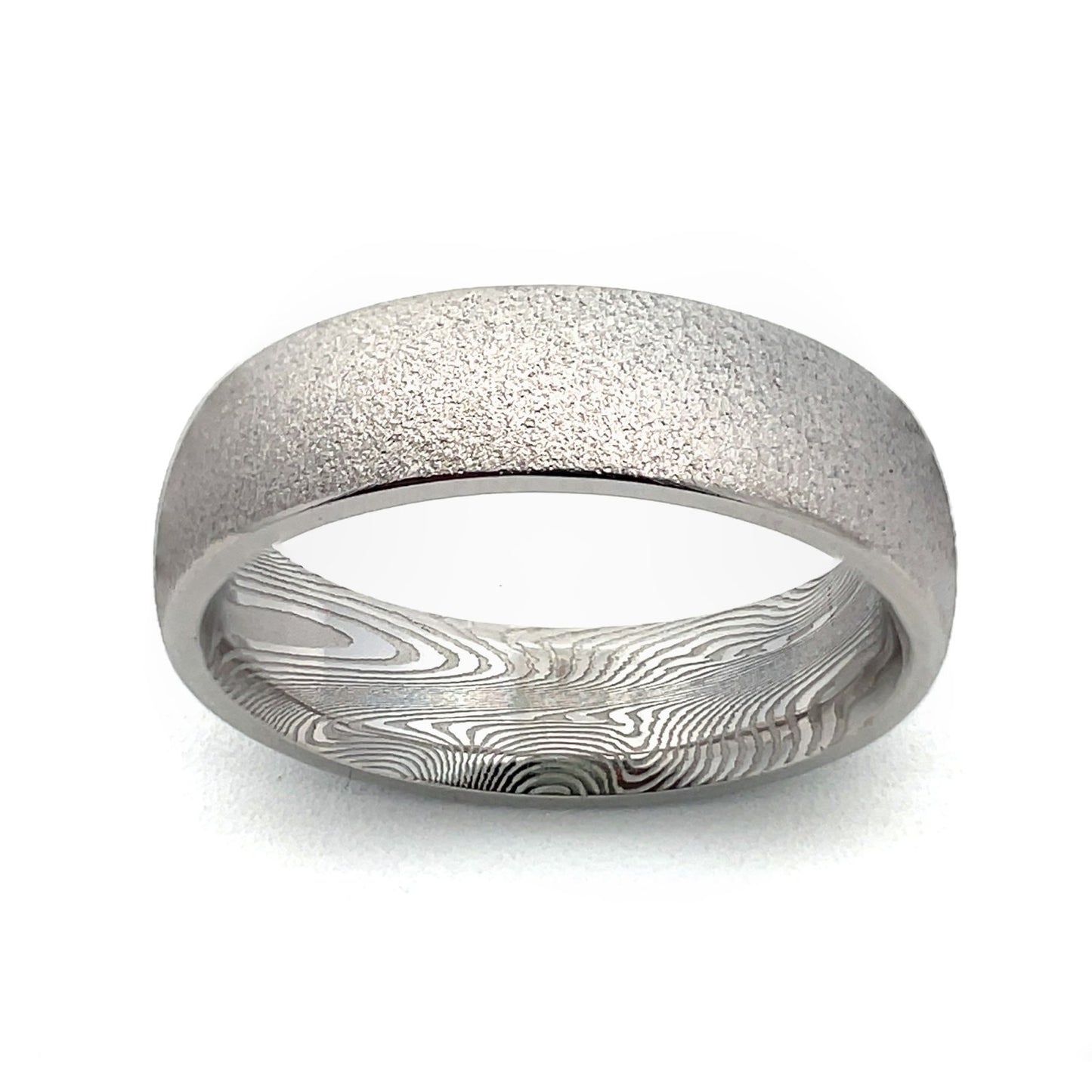 Stainless steel ring with a Damascus steel pattern on the inside, on a white background.