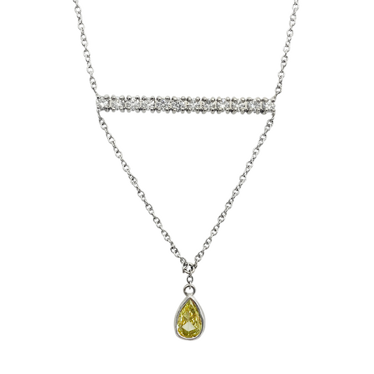 Silver necklace with a delicate chain and a pear-shaped yellow gemstone pendant. The chain features a horizontal bar adorned with smaller stones.