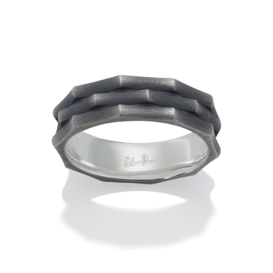 Silver ring with a textured, geometric pattern on a white backgroun