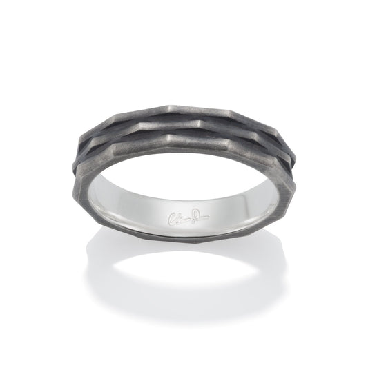 Silver ring with a textured, geometric pattern on a white backgroun