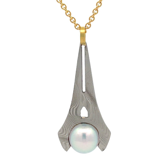 Silver pendant shaped like a stylized arrowhead, with a swirling, Damascus steel pattern and a pink pearl in the center, on a white background.