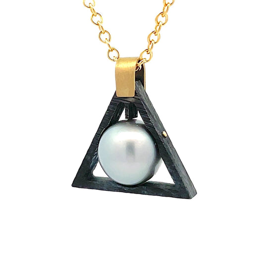 Gold chain necklace with a black triangular pendant holding a pink pearl in the center, on a white background.