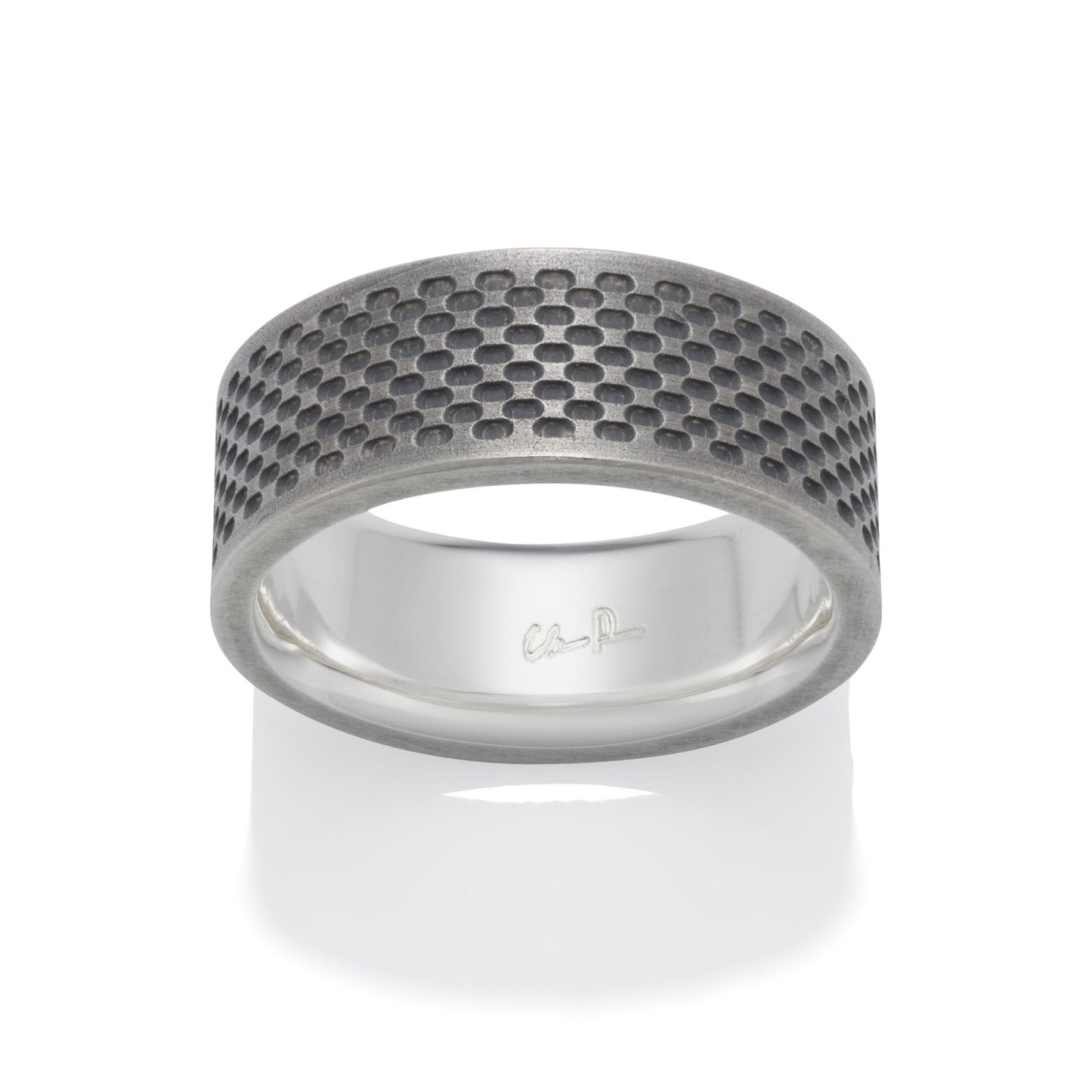 Silver ring with a textured, honeycomb pattern on a white background