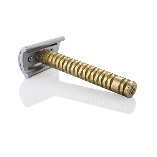 Razor with a textured gold handle and a silver-colored blade head, on a white background