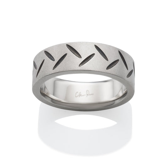 Silver ring with a textured pattern featuring black lines, on a white background.