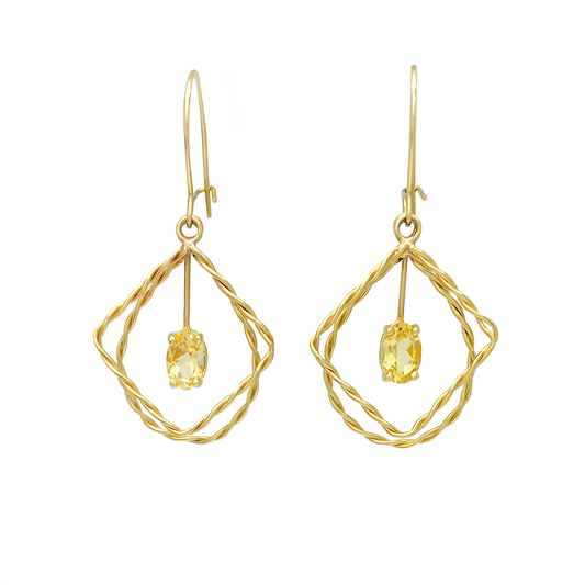 Gold drop earrings with a yellow citrine gemstone within a geometric wire frame on a white background.